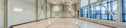 A large, empty gymnasium with wooden floors and a high ceiling.