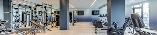 A gym with a variety of equipment including weights, treadmills, and stationary bikes.
