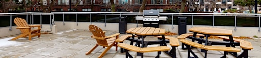 A patio with wooden chairs and tables is empty.