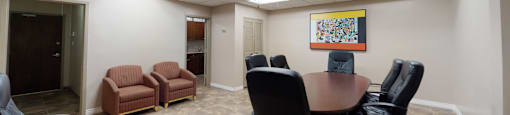 A conference room with a table, chairs, and a painting on the wall.
