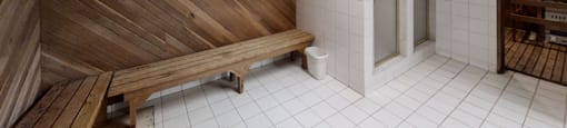 A wooden bench is placed in a room with a white tiled floor.