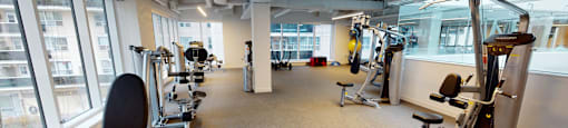 A gym with a variety of equipment including treadmills, weights, and exercise machines.