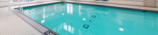 A large indoor swimming pool with a tiled floor and a glass wall at Vivere.