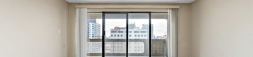 Empty room with a large window and wooden flooring.