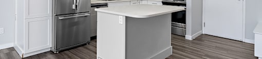 A kitchen with white cabinets and a stainless steel refrigerator.
