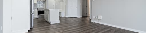 A spacious room with wooden flooring and white walls.