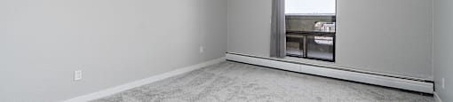 A room with a window and carpeted floor.