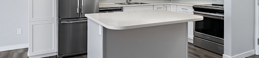 A modern kitchen with a refrigerator, sink, and stove.