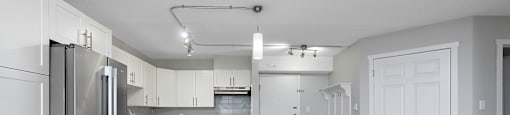 A modern kitchen with white cabinets and a stainless steel refrigerator.