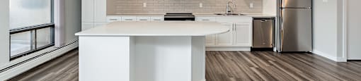 A modern kitchen with a white island and stainless steel appliances.