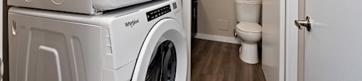 A white washing machine and dryer stacked on top of each other in a small laundry room.