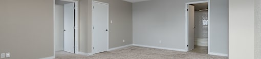 A spacious room with carpeted floor and three doors.