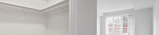 A white room with a carpeted floor and a door leading to a hallway.
