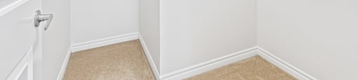 A white closet with a shelf and a door.