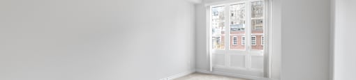 A room with white walls and carpeted floor with a window.