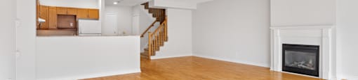 A large empty room with wooden floors and a fireplace.