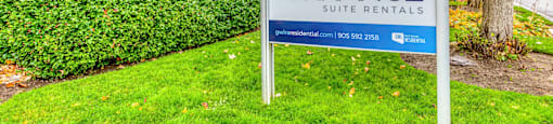 a sign in the grass in front of an apartment building