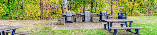a group of picnic tables and garbage cans in a park