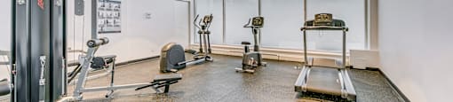 a gym with treadmills and weights on the floor and a large window