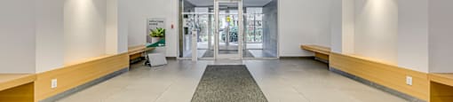 a large white lobby with a rug in the middle and a glass door