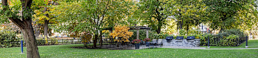 a park with green grass and trees and a fountain