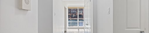 a hallway with white walls and a door to a room with a window