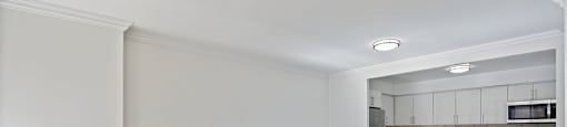 an empty living room with a kitchen in the background