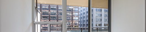 an empty room with a large window and roller blinds