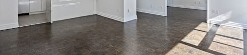 an empty living room with a kitchen in the background