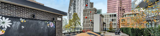 A black and orange striped area with rocks in the middle and a building with a mural on the side.