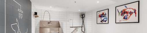 A bathroom with a large mirror and two artworks on the wall.