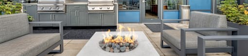 A modern outdoor seating area with a fire pit in the center.