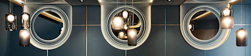 A modern restaurant with a curved pink sofa and round mirrors on the wall.