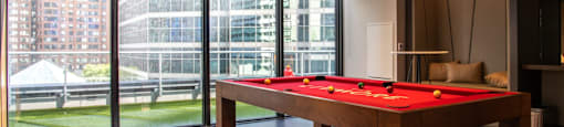 A pool table in a room with a view of the outside.