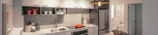 A modern kitchen with a white countertop and stainless steel appliances.