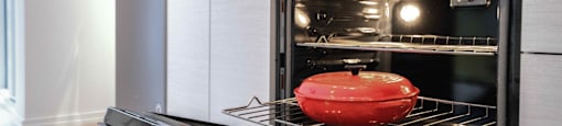 A red pot is sitting on the rack of an oven.