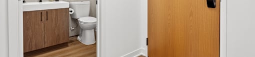 a door leading into a bathroom with a toilet and a sink