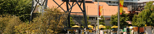 A yellow crane is on a dock with a building in the background.