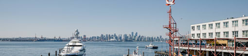A boat is docked at a pier with a city skyline in the background.