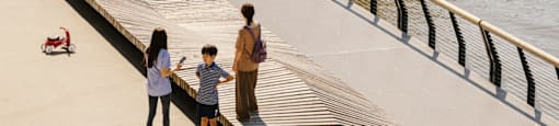 A group of people are walking on a boardwalk near a body of water.