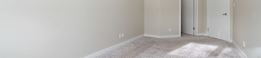 A room with a carpeted floor and two doors.