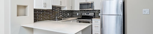 A kitchen with a white counter top and stainless steel appliances.