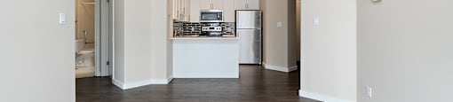 A kitchen area with a refrigerator, sink, and cabinets.