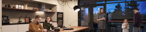 A family is gathered in a modern kitchen and dining area.