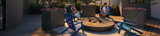 Two people sitting around a fire pit on a rooftop patio.