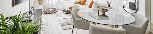 A modern dining room with a glass table and grey chairs.