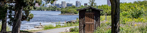 a path leading to a wooden outhouse next to a river