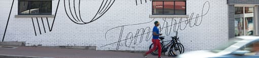 a man walks past a mural on the side of a building