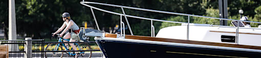a person riding a bike on a dock next to a boat