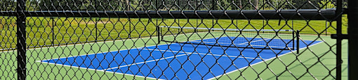 A blue and yellow umbrella is attached to a black fence.